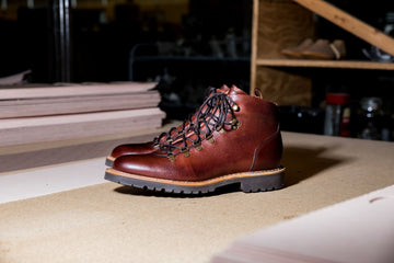 Brown leather boots and shoemaking tools on a workshop table